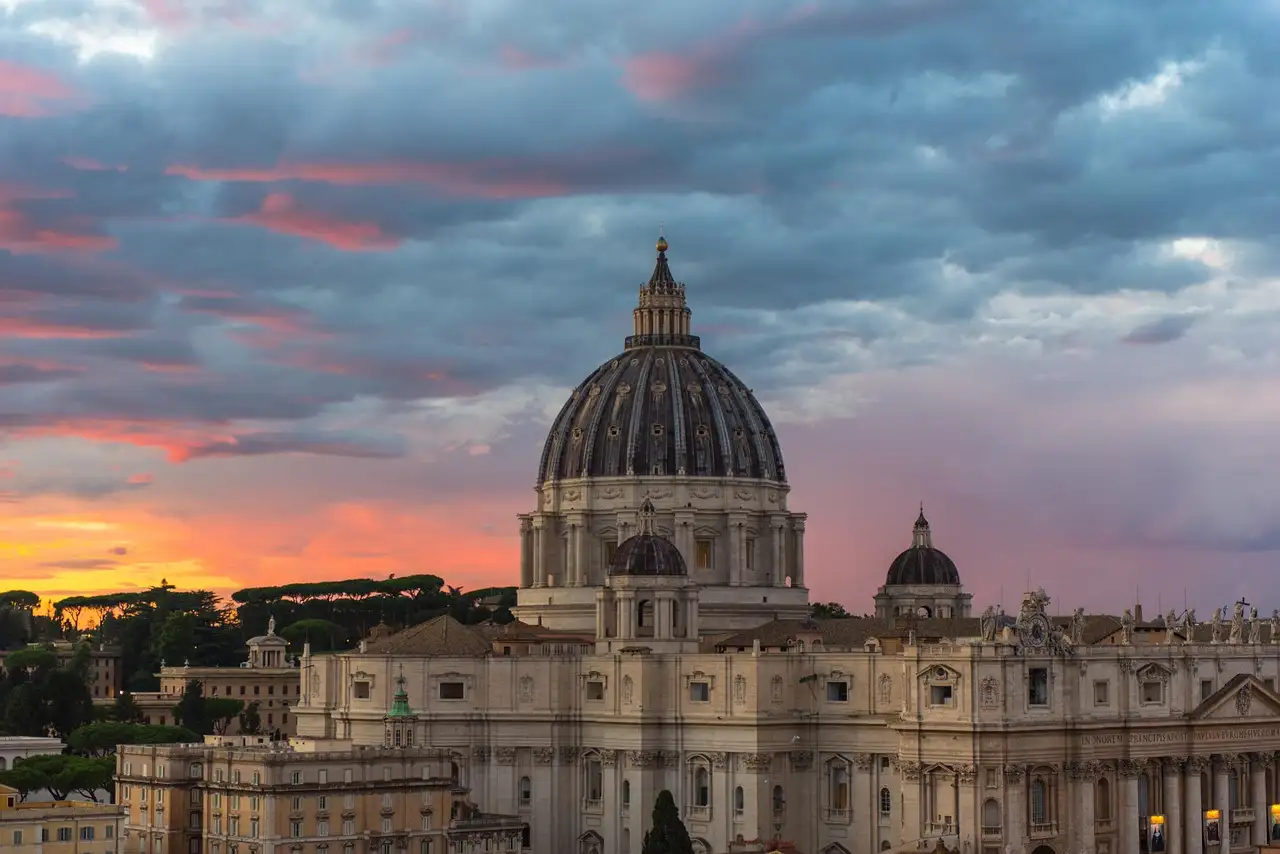 The dome of St. Peter's Basilica against a pink and grey evening sky
