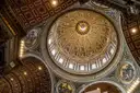 The inside of St. Peter's dome seen from below, with gold and coffered panels