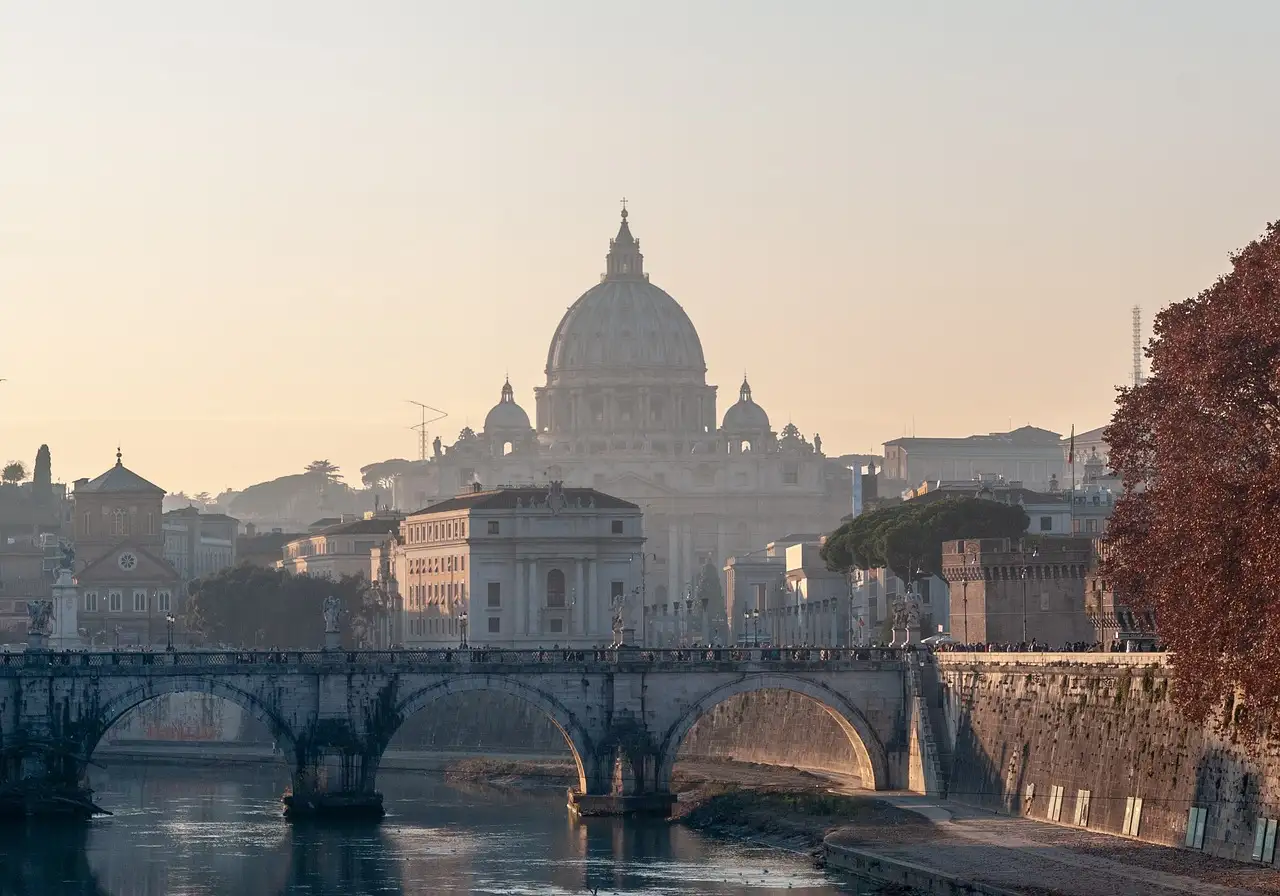 The dome of St. Peter's Basilica behind a bridge over the Tiber at sunset
