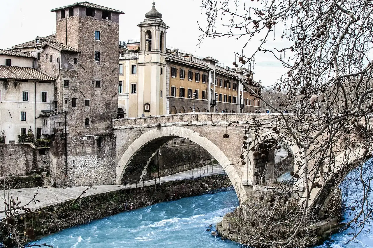 An old stone bridge over the Tiber with the buildings of Tiber Island