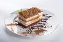 A slice of layered tiramisu dusted with cocoa on a white plate