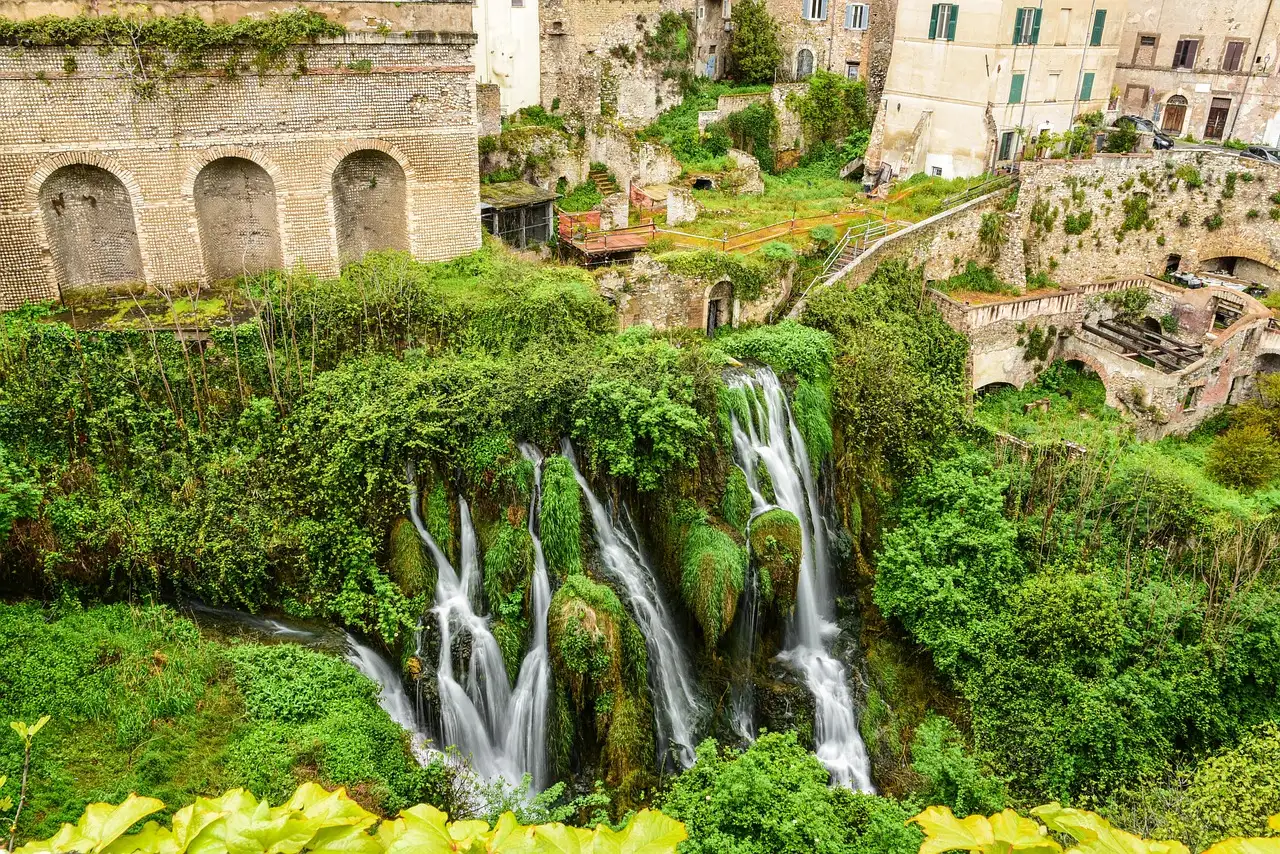 Waterfalls tumbling down a green gorge below the old town of Tivoli