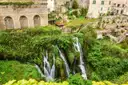 Waterfalls tumbling down a green gorge below the old town of Tivoli