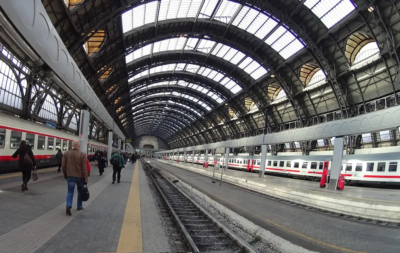 Platforms and trains under the large iron-and-glass roof of Milano Centrale station