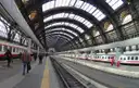 Platforms and trains under the large iron-and-glass roof of Milano Centrale station