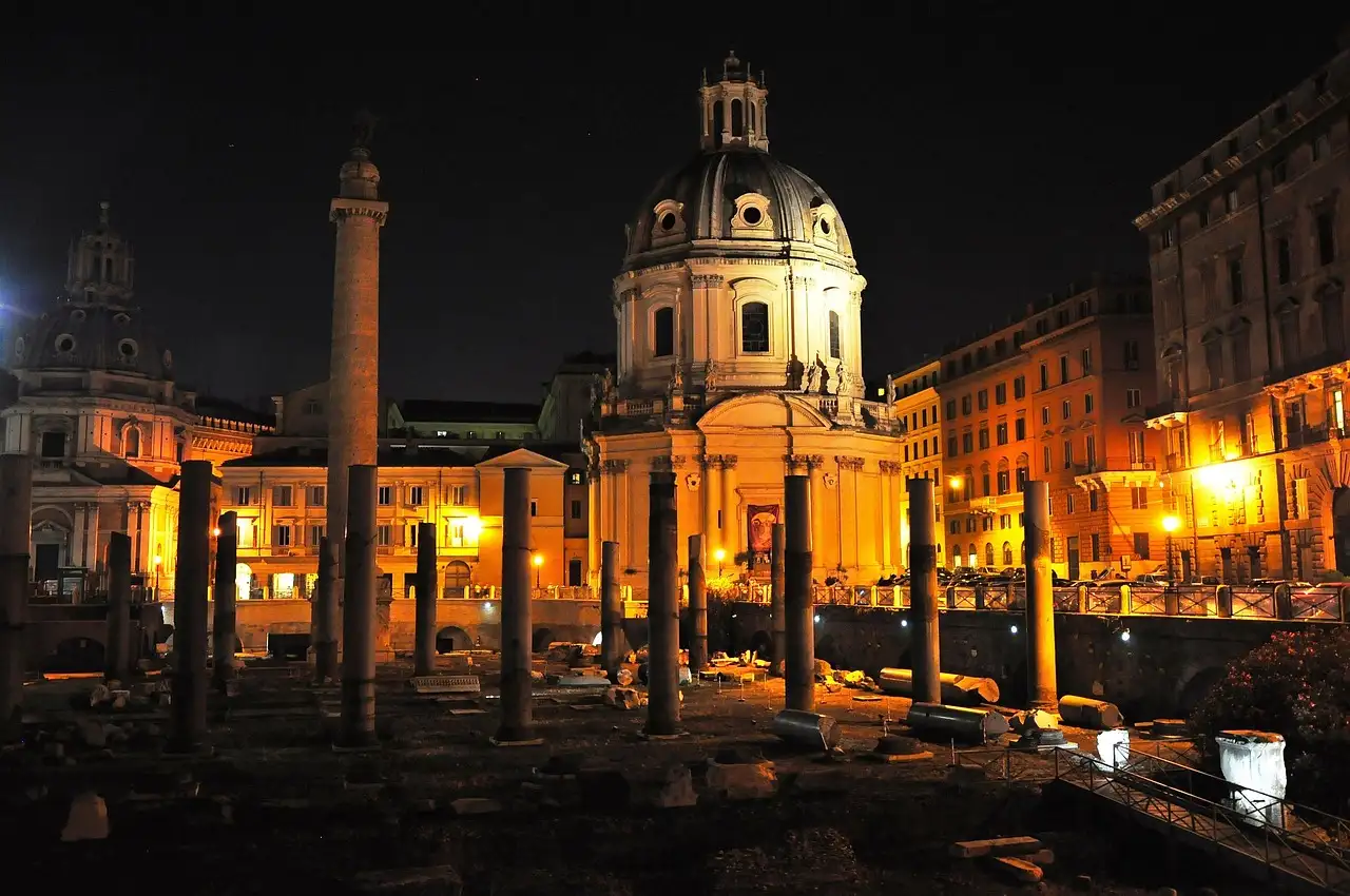 Trajan's Column and the old forum lit up at night, with a domed church behind