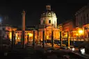 Trajan's Column and the old forum lit up at night, with a domed church behind