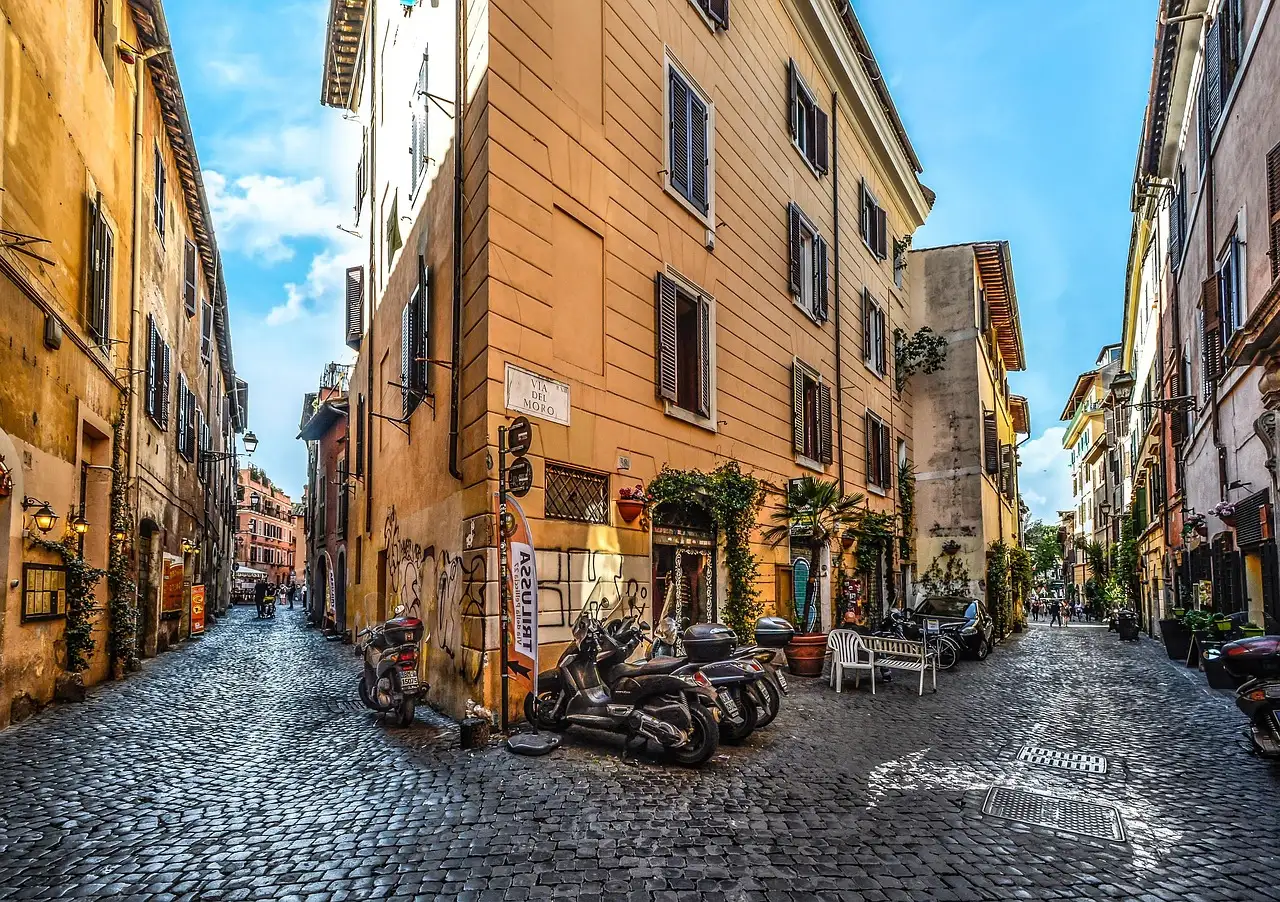 A cobbled lane in Trastevere with warm-colored houses and parked scooters