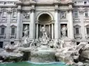 The Trevi Fountain in Rome in daylight, with its white statues and turquoise water