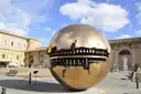 A large bronze sphere sculpture in a courtyard of the Vatican Museums