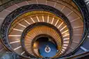 The spiral staircase of the Vatican Museums seen from above, lit in gold
