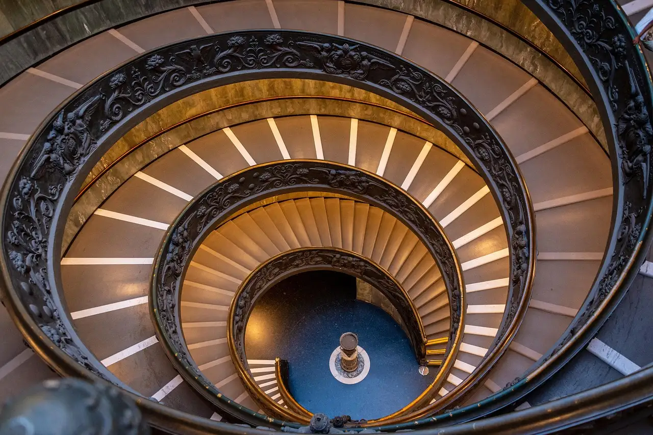 The spiral staircase of the Vatican Museums seen from above, lit in gold