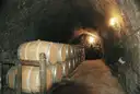 Wine barrels lined up in a cave cellar with stone walls